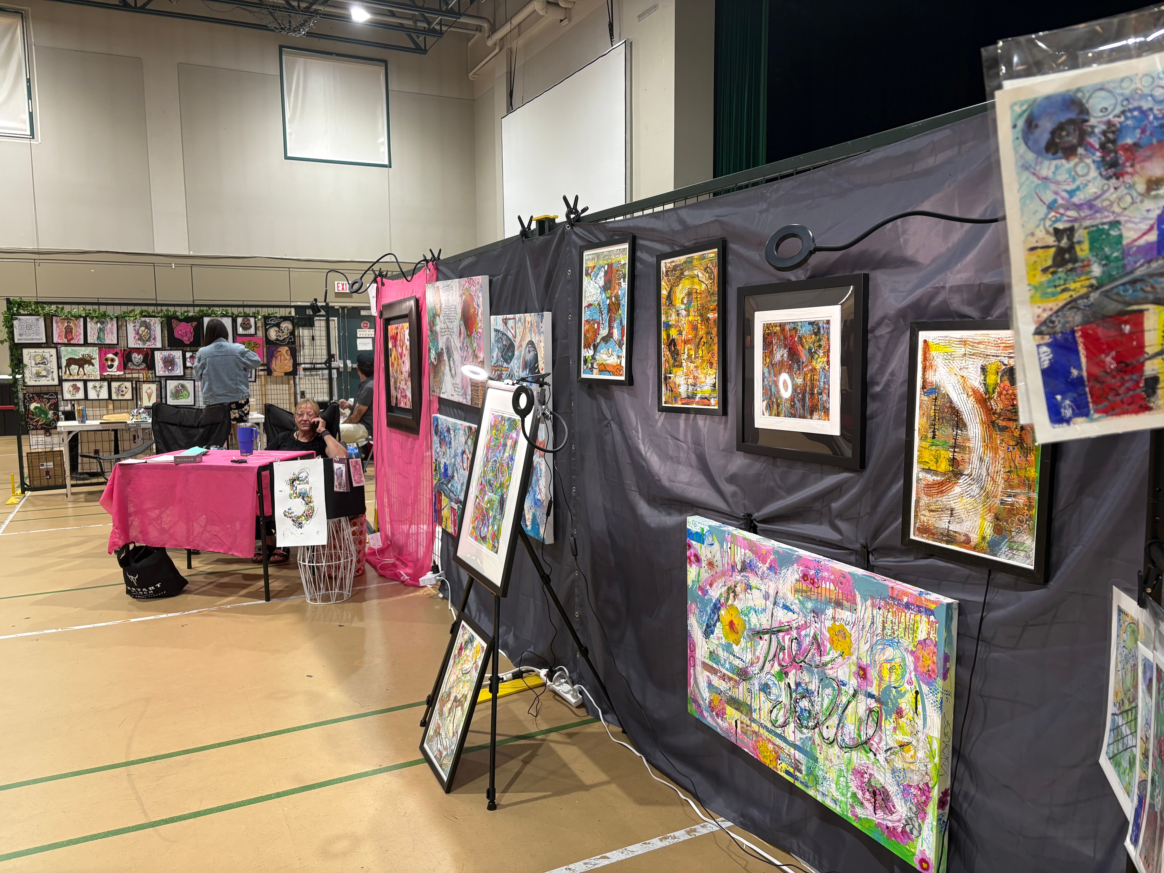 Dana Corkey displaying colorful mixed media paintings at exhibition